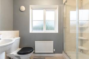 uma casa de banho com um WC, um lavatório e uma janela em 3-Bedroom Home in Peterborough with Free Parking & Netflix by HP Accommodation em Peterborough