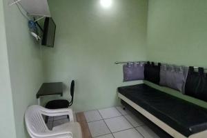 a small room with a bed and a chair in it at Bertioga Praia Guaratuba - Condomínio Costa do Sol in Bertioga