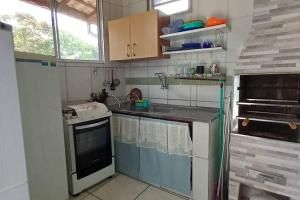 a small kitchen with a sink and a stove at Bertioga Praia Guaratuba - Condomínio Costa do Sol in Bertioga