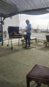 a man is standing next to a grill at Montevideo Port Hostel in Montevideo