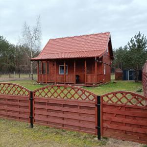 a wooden house with a fence in front of it at Domek u Natalii 