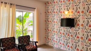 a room with a tv and two chairs and a window at Pebbles 2BHK Home By Goaround Homes in Siolim