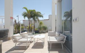 eine Terrasse mit Tischen, Stühlen und Palmen in der Unterkunft Villa 26 - 7 bedrooms with private pool in Eilat