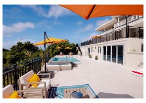 a balcony with a pool and chairs and an umbrella at Luxurious Oasis for groups in Rodney Bay Village