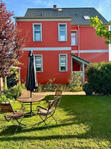 a table and chairs and an umbrella in front of a house at Ferienwohnung Mathilda in Waren