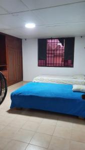 een slaapkamer met een blauw bed en een raam bij Hostal las flores de Valledupar in Valledupar