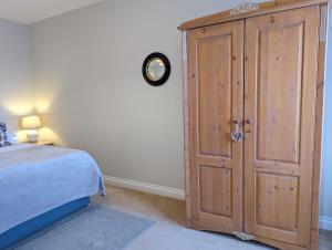 a bedroom with a large wooden cabinet next to a bed at Little Chilsbury in Potterne