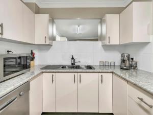 a kitchen with white cabinets and a sink at Glenmore Lodge - CBD Location, Hidden Gem in Dubbo