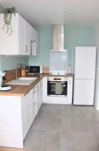 a kitchen with white cabinets and a white refrigerator at Apptartement neuf - Situation idéale - Balnéo - Parking in Mérignac