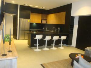 a kitchen with white stools and a black counter at Romance en Sail View Vallarta in Puerto Vallarta