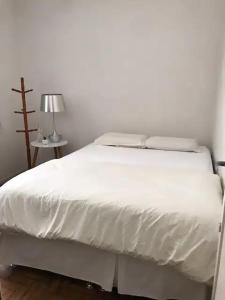 a white bed in a room with a lamp at Bucolico Apartamento em Copacabana in Rio de Janeiro