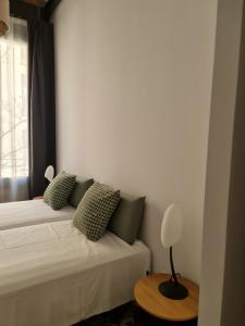 a bedroom with a bed with green pillows and a window at Poble Sec Charming Apartment in Barcelona