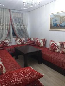 Una sala de estar con sofás rojos y una mesa. en الدار البيضاء بوركون, en Aïn Harrouda