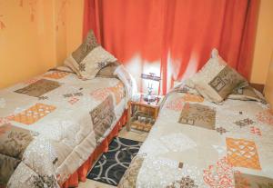 2 camas en una habitación con cortinas rojas en Hotel Rodelu, en Latacunga