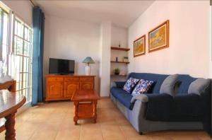 Una sala de estar con un sofá azul y un televisor en AyD, en Nerja