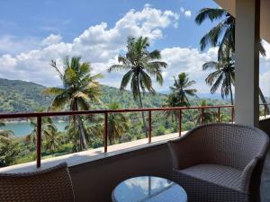 a balcony with chairs and a table and palm trees at Par 5 Golf Villa in Digana