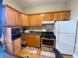 a kitchen with wooden cabinets and a white refrigerator at Enjoyapt Patio, Ready4all Kind The Whether in West New York