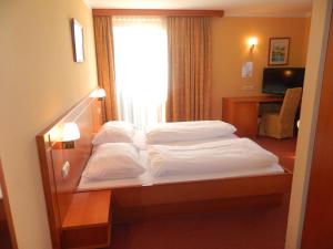 two beds in a hotel room with a window at Gasthaus - Pension Kärntnerhof in Faak am See