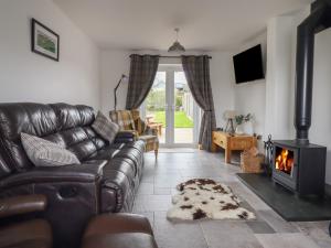 a living room with a leather couch and a fireplace at Gwynfa in Bala