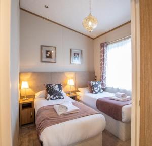 a hotel room with two beds and a window at Hot Tub Lodge 26 Cameron, St Andrews in St. Andrews