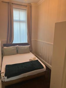 a small bed in a room with a window at Entire 4br with cot, free street parking and garage in Sunderland