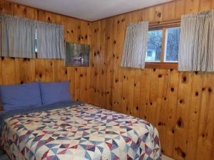 1 dormitorio con 1 cama con paredes y ventanas de madera en Hidden Harbor Moorings, en Minocqua
