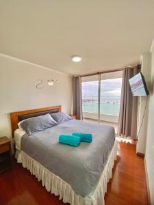 a bedroom with a bed with two blue pillows on it at Apartamento Alma Capital in Iquique +36 photos