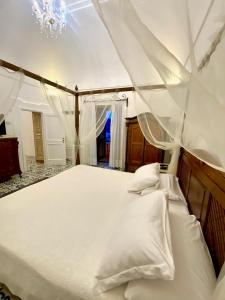 una camera da letto con un letto con lenzuola bianche e un lampadario a braccio di Villa Principe Giovanni a Positano