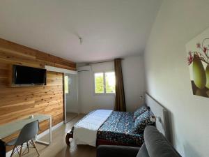 a bedroom with a bed and a desk and a couch at GITE PEI LA VANILLE "Studio Cosy en Bord de Nature" in Sainte-Suzanne