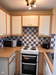 a kitchen with a stove and a microwave at Stunning one bed Apartment with free Wifi and Parking in Goodmayes