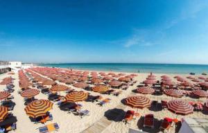 a large group of umbrellas and chairs on a beach at Case Vacanza Dimo Dimira - SALENTO & RELAX in Torre Chianca