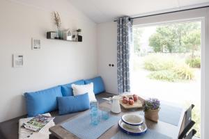 a living room with a table and a blue couch at Bungalow Bord de mer in Gouville-sur-Mer