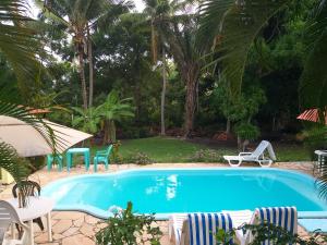 einen Pool im Garten mit Stühlen und einem Tisch in der Unterkunft Pousada Vila Imbassai in Imbassai