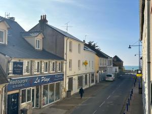 une personne marchant dans une rue à côté des bâtiments dans l'établissement Appartement Cote des Isles, à Barneville-Carteret