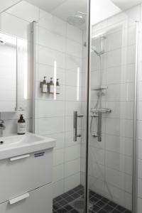 a white bathroom with a shower and a sink at Duveslätt B & B in Åskloster +12 photos