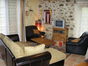 ein Wohnzimmer mit Ledersesseln und einem TV in der Unterkunft GITE la Rocaille in Sevremont