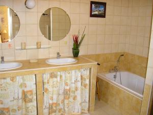 ein Badezimmer mit zwei Waschbecken und einer Badewanne und Spiegeln in der Unterkunft GITE la Rocaille in Sevremont + 1 Foto