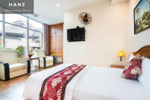 ein Hotelzimmer mit einem Bett und einem TV in der Unterkunft HANZ Queen Airport Hotel in Ho-Chi-Minh-Stadt