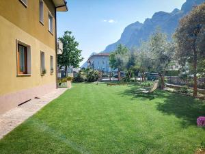 a yard with benches and a building with mountains in the background at Villa Citrus in Riva del Garda