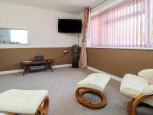 a room with two chairs and a tv and a table at Flat 1 Marina Court in Redruth