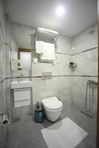 a white bathroom with a toilet and a sink at Yuvam akmarmara hotel in Istanbul