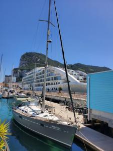 un velero atracado en un puerto deportivo con un edificio en LUXURY YACHT STAY "White Dove" sleeps 6 en Gibraltar