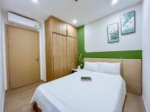 a bedroom with a white bed with a green wall at The Song Boutique Vung Tau in Vung Tau