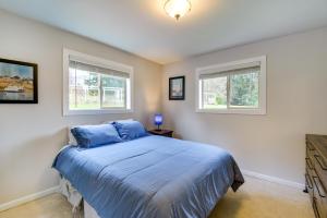 Un dormitorio con una cama azul y dos ventanas. en Port Townsend Home Spacious Yard and Mountain Views, en Port Townsend
