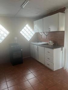 a kitchen with white cabinets and a tile floor at The Space Guesthouse in Vryheid