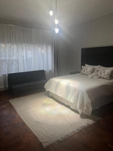 a bedroom with a white bed and a large window at The Space Guesthouse in Vryheid