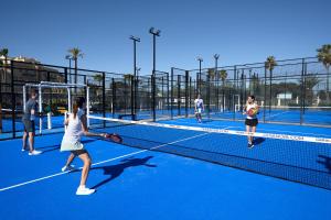 un groupe de personnes jouant au tennis sur un court de tennis dans l'établissement Levante by Oliva Nova, à Oliva