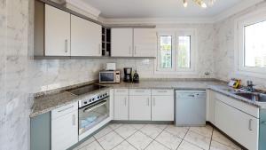 Una cocina blanca con gabinetes y electrodomésticos blancos. en Villa Golden by ON Travel, en Oliva