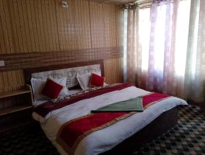 a bedroom with a large bed with red pillows at Milam Cottage in Leh