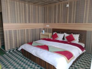 a bedroom with a large bed with red and green pillows at Milam Cottage in Leh